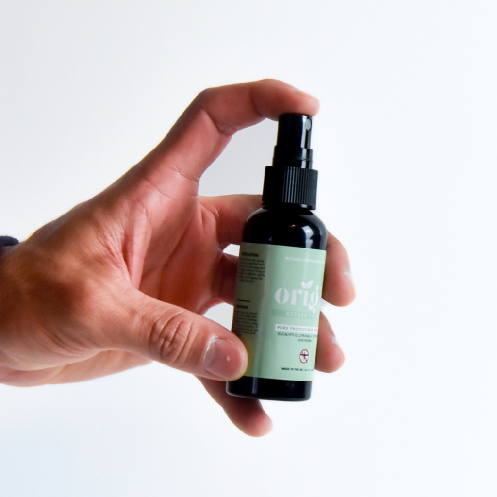 Hand holding Pure Protect bug repellent spray bottle