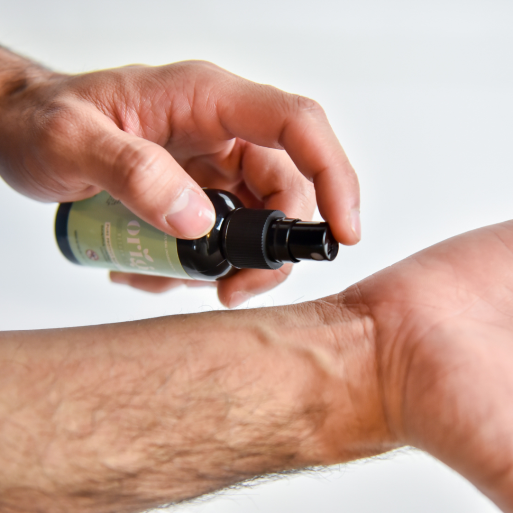 Applying natural bug repellent spray to arm